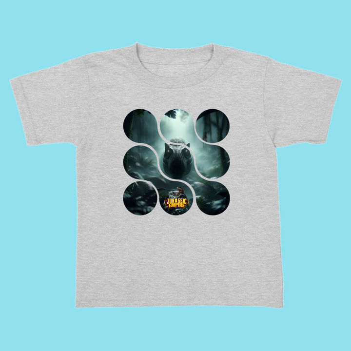 The Toddler Jurassic Empire T-Rex T-Shirt by Jurassic Studio features a dinosaur in a misty forest, circular design, and Jurassic Park logo—perfect for dino fans and exclusive to the brand. Displayed on a light blue background.
