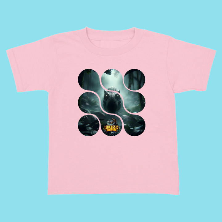 The Toddler Jurassic Empire T-Rex T-Shirt by Jurassic Studio is a light pink tee with a dinosaur graphic, black circles and rounded shapes, and a Jurassic World logo—an ideal gift for dino fans, shown on a plain light blue background.