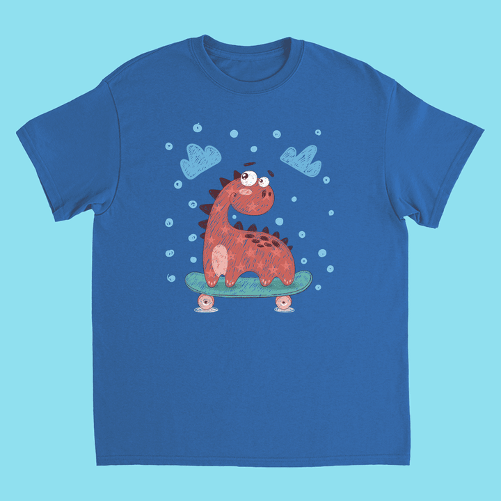 The Kids Baby Dino Skate T-Shirt by Jurassic Studio features a cute red cartoon dinosaur riding a green skateboard, with blue clouds and bubbles on a light blue background.