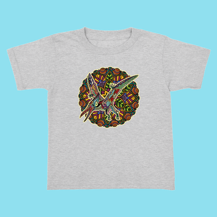 The Toddler Pterodactyl Mandala T-Shirt by Jurassic Studio features a vibrant, patterned pterodactyl with a fiery circular background—perfect for little dinosaur fans! Displayed on a bright blue backdrop.