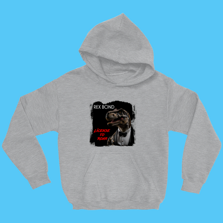 The Kids Rex Bond Hoodie by Jurassic Studio features a gray design with a T. rex in a suit and bowtie, REX BOND in white, LICENSE TO ROAR in red, and a light blue background—perfect for any dinosaur fan.