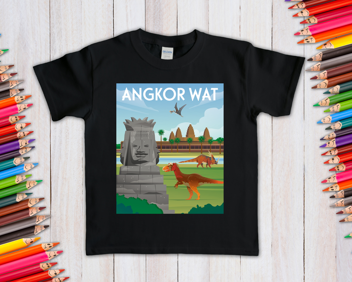 The Kids Angkor Wat T-Shirt by Jurassic Studio features a black shirt with an illustrated scene of a stone face, trees, dinosaurs, and a pterosaur, displayed among colored pencils on a wooden surface.