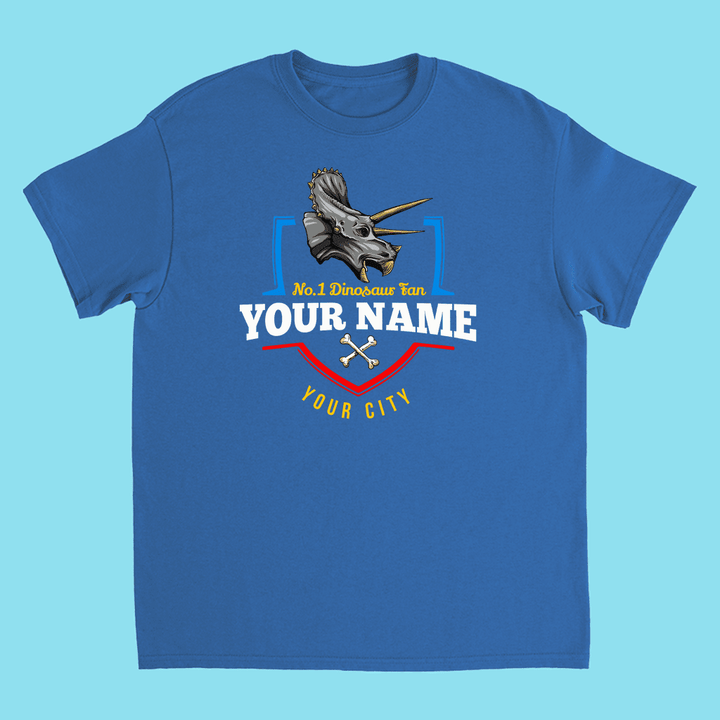 The N.1 Triceratops Fan Custom Kids T-Shirt by Jurassic Studio features a triceratops head, “No. 1 Dinosaur fan YOUR NAME YOUR CITY,” crossed bones, and colorful details—a perfect personalized dinosaur gift for kids.