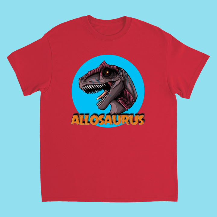 The Kids Allosaurus Head T-Shirt by Jurassic Studio features a bold red design with a dinosaur head in a blue circle and ALLOSAURUS in textured yellow—a perfect gift for young dinosaur fans.