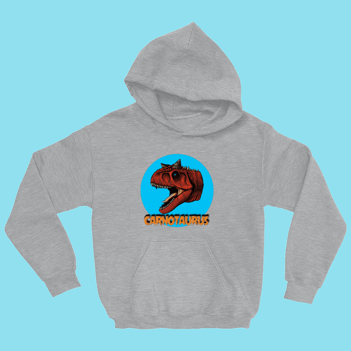 The Kids Carnotaurus Head Hoodie by Jurassic Studio features a gray hoodie with a red dinosaur head inside a blue circle, bold orange CARNOTAURUS text below, and a light blue background—perfect for young dinosaur fans.