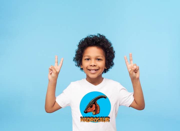 A smiling child with curly hair flashes peace signs while wearing the Jurassic Studio Kids Hadrosaur Head T-Shirt, featuring an illustrated hadrosaur on blue—a perfect gift for young dinosaur fans.