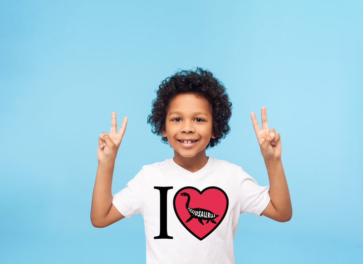 A smiling child with curly hair flashes peace signs, wearing a white Kids I Love Plesiosaurus T-Shirt by Jurassic Studio—a perfect gift for dinosaur fans—against a light blue background.