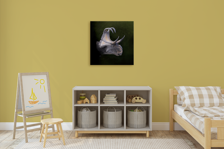 A children’s room with yellow walls and checked bedding feels playful, featuring the Jurassic Studio Triceratops Portrait Canvas Wrap as vibrant wall art above shelves of baskets, toys, and an easel with a sun and sailboat drawing.