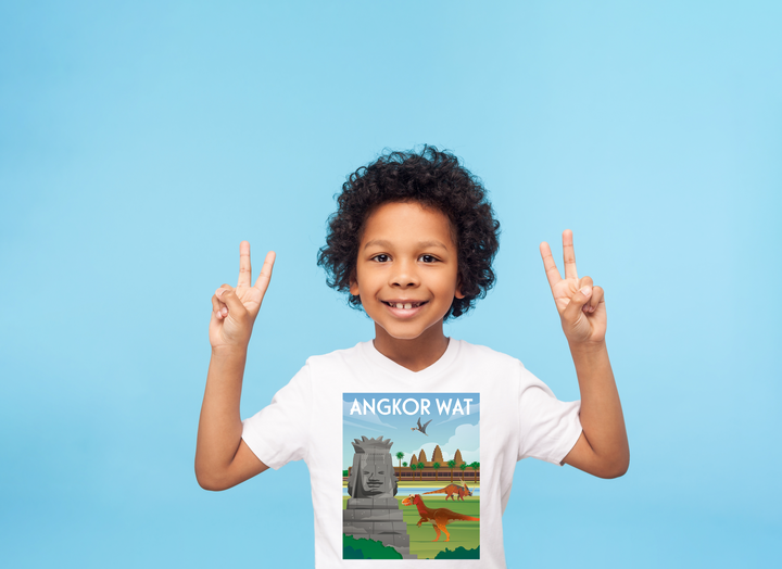 Smiling child with curly hair on a blue background, flashing peace signs and wearing the Jurassic Studio Kids Angkor Wat T-Shirt, which showcases a colorful illustration and bold text.