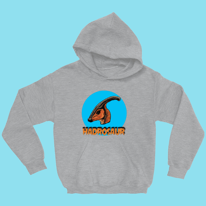 The Kids Hadrosaur Head Hoodie by Jurassic Studio features a gray hoodie with a vibrant Parasaurolophus head in a blue circle above bold orange HADROSAUR, displayed on a light blue backdrop.