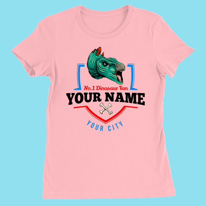 Jurassic Studio’s N.1 Stegosaurus Fan Custom Women T-Shirt features a pink slim fit, cartoon stegosaurus head, crossed bones, and “N.1 Dinosaur Fan” text with your name and city on a blue background.