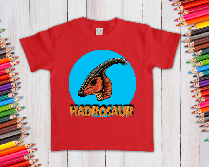 The Kids Hadrosaur Head T-Shirt by Jurassic Studio features a red tee with a vibrant hadrosaur head before a blue circle, HADROSAUR in bold below, framed by colored pencils—a great gift for young dinosaur fans!.