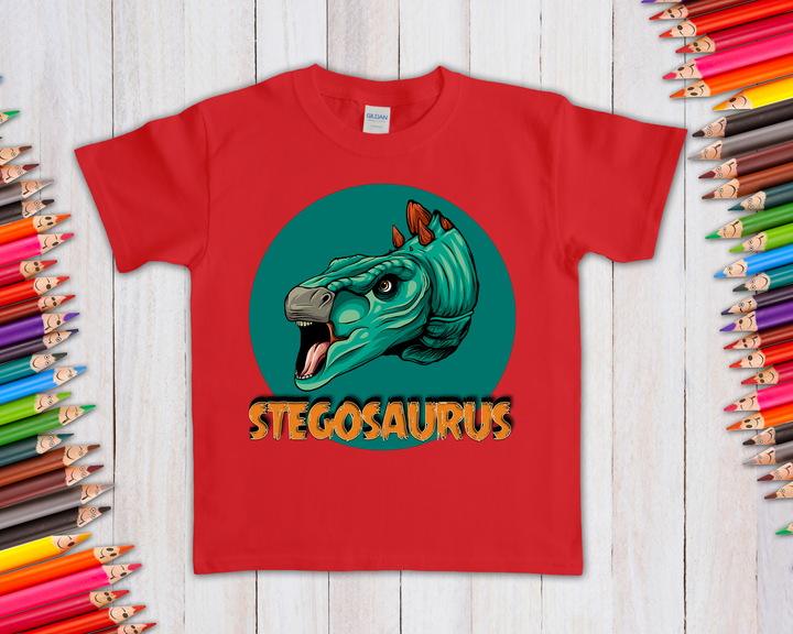 The Kids Stegosaurus Head T-Shirt by Jurassic Studio features a cartoon stegosaurus in a teal circle with bold orange STEGOSAURUS text and colorful pencils—a fun gift for any dinosaur fan.