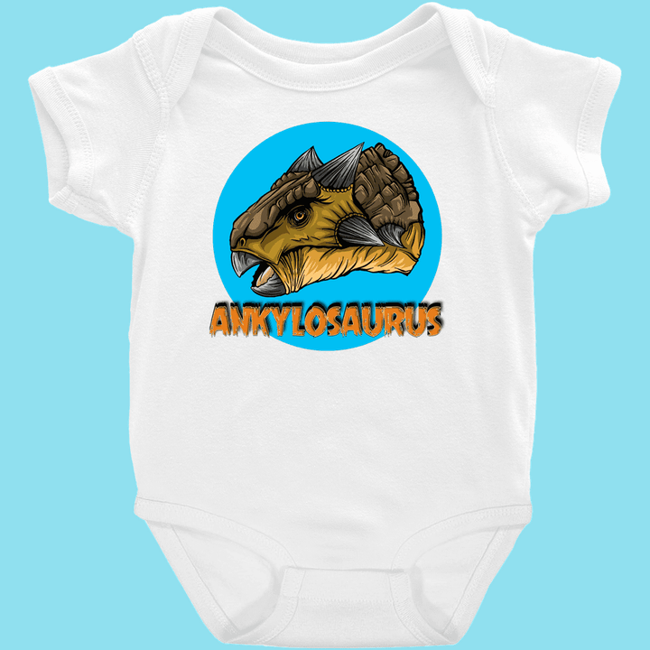 The Toddler Ankylosaurus Head Onesie by Jurassic Studio features a circular Ankylosaurus head illustration and bold orange ANKYLOSAURUS text on white, set against a light blue background—a Jurassic Studio exclusive.