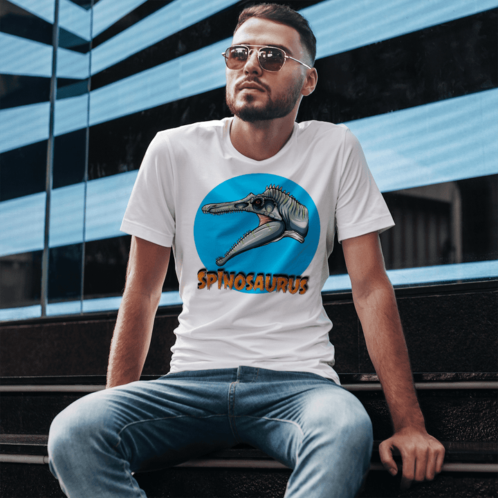A man in sunglasses wears a Men Spinosaurus Head T-Shirt by Jurassic Studio, seated on steps before a modern blue and black building—a perfect dinosaur fan gift.