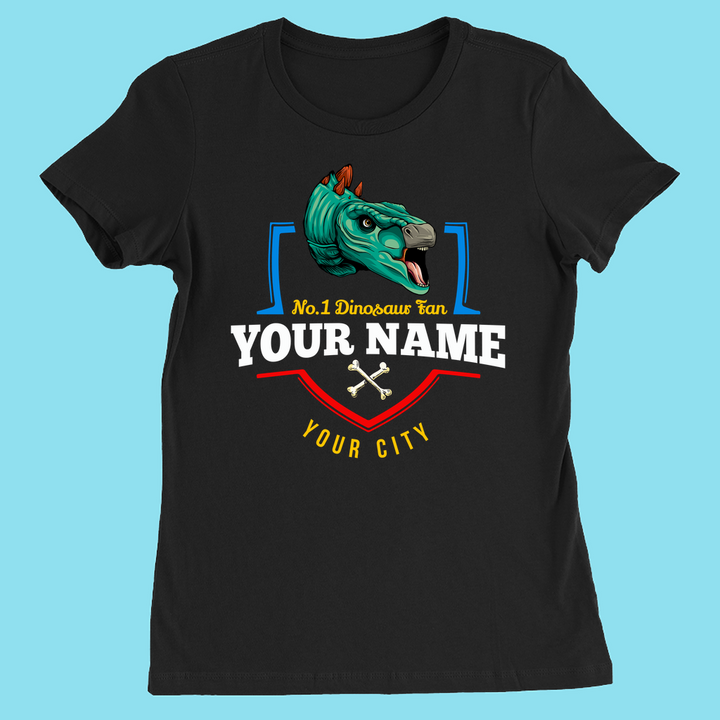 The N.1 Stegosaurus Fan Custom Women T-Shirt by Jurassic Studio is a slim fit shirt with a cartoon dino head, No. 1 Dinosaur Fan text, Your Name and City customization, two crossed bones, and a light blue background.