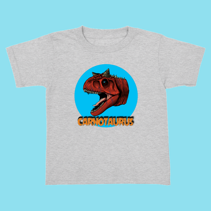 Jurassic Studio’s Toddler Carnotaurus Head T-Shirt features a gray tee with a red Carnotaurus head in a blue circle and bold orange CARNOTAURUS text—a perfect gift for little dinosaur fans.