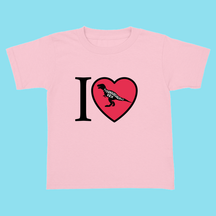The Toddler I Love T-Rex T-Shirt by Jurassic Studio features a light pink design with an “I ♥ Tyrannosaurus Rex” print—the heart holds a black T. rex silhouette and text. Displayed on blue, its perfect for little dinosaur fans.