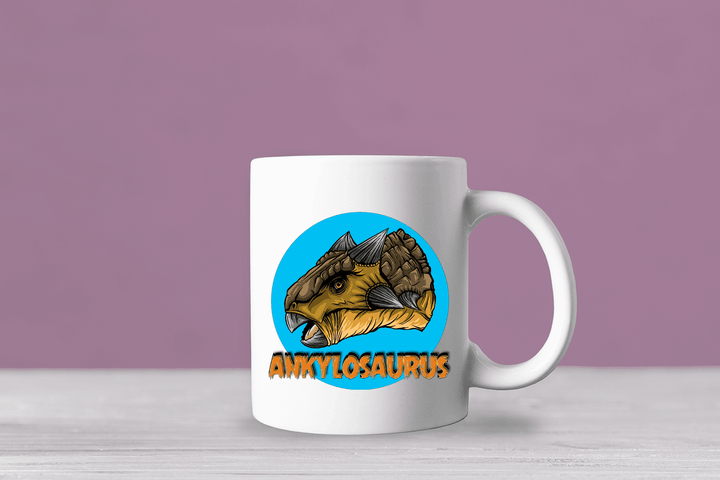 The Ankylosaurus Portrait Mug by Jurassic Studio features a colorful ankylosaurus head in a blue circle, bold orange ANKYLOSAURUS text below, and a light purple background for a playful prehistoric look.