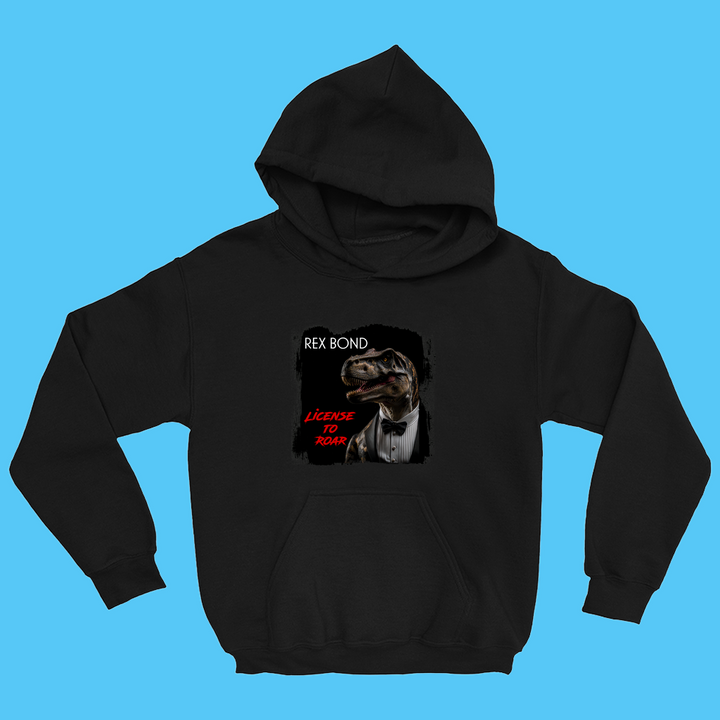 The Kids Rex Bond Hoodie by Jurassic Studio features a tuxedoed dinosaur parodying James Bond, with bold white and red “REX BOND” and “LICENSE TO ROAR” text on a blue background—perfect for kids or dino fans.