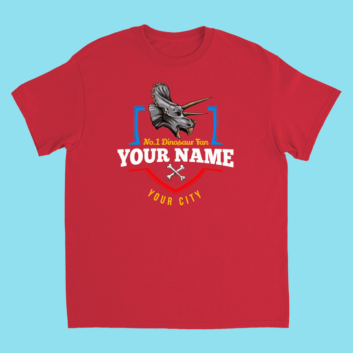 Jurassic Studio’s N.1 Triceratops Fan Custom Kids T-Shirt features a red triceratops head, “No.1 Dinosaur Fan,” YOUR NAME, and YOUR CITY with crossed bones—an ideal personalized dino gift on a light blue background.