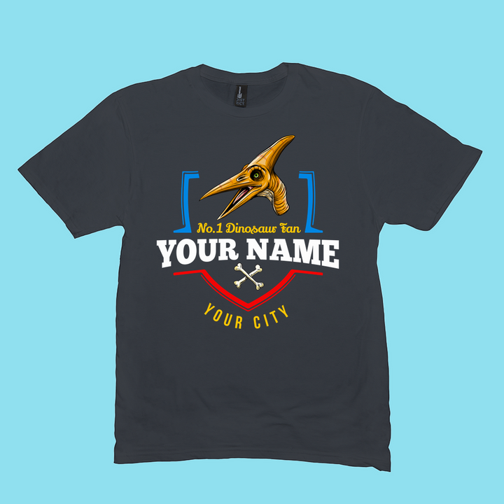 Jurassic Studios N.1 Pterodactyl Fan Custom Men T-Shirt features a yellow pterosaur head, No.1 Dinosaur Fan text, your name and city, two white crossed bones, and a light blue background—exclusively personalized for you.