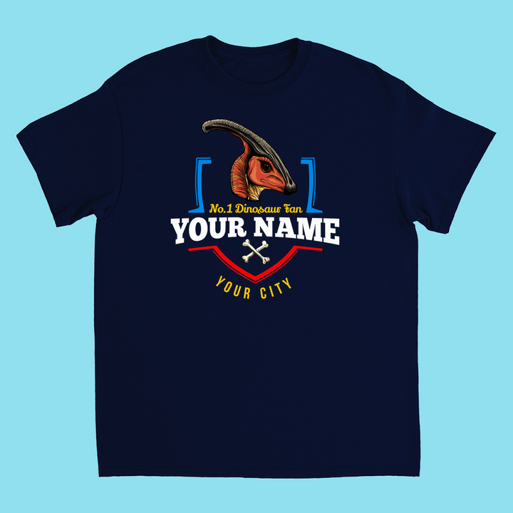 Jurassic Studio’s N.1 Hadrosaur Fan Custom Kids T-shirt in navy blue features an illustrated parasaurolophus, No.1 Dinosaur Fan YOUR NAME and YOUR CITY—decorated with lines and crossed bones, making it a perfect dinosaur gift!.