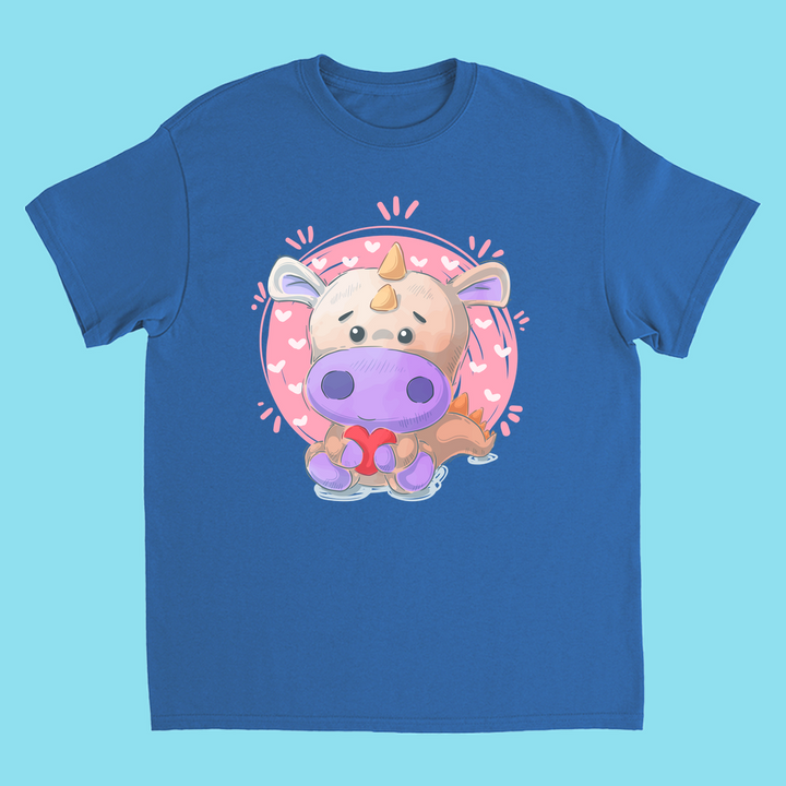 Jurassic Studio’s Kids Pink Baby Dino T-Shirt features a cute chubby cartoon dinosaur with a purple snout and orange horn, holding a red bow, centered on a pink circle with hearts.
