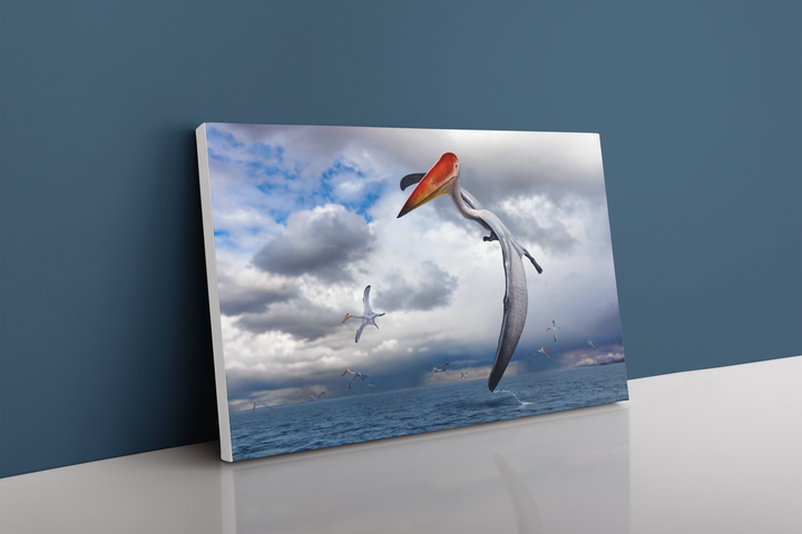 The Azhdarcho Flying Canvas Wrap by Jurassic Studio features majestic prehistoric flying reptiles gliding over the ocean under a cloudy sky, shown resting against a blue wall.