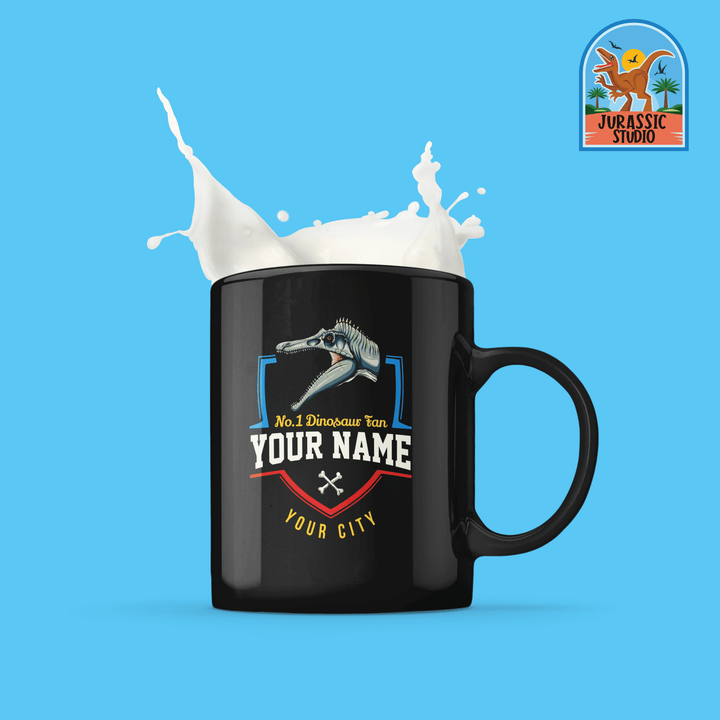 The N.1 Spinosaurus Fan Custom Mug by Jurassic Studio features a black mug with a dinosaur skull graphic, customizable text, and is filled with splashing milk. The top right corner displays the Jurassic Studio logo on a blue background.