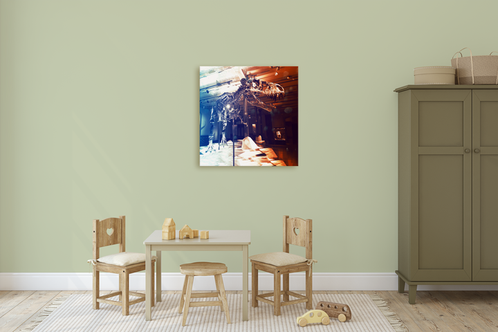 A childrens playroom with a small table, wooden chairs, toys, and an olive-green wardrobe against a light green wall features the Jurassic Studio T-Rex Full Skeleton Canvas Wrap above the table, adding playful charm to the space.