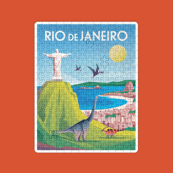 The Rio de Janeiro Puzzle by Jurassic Studio showcases Christ the Redeemer, pterosaurs, a glowing sun, mountains, ocean, and cityscape on a vivid red background—a fun jigsaw for any family game night!.