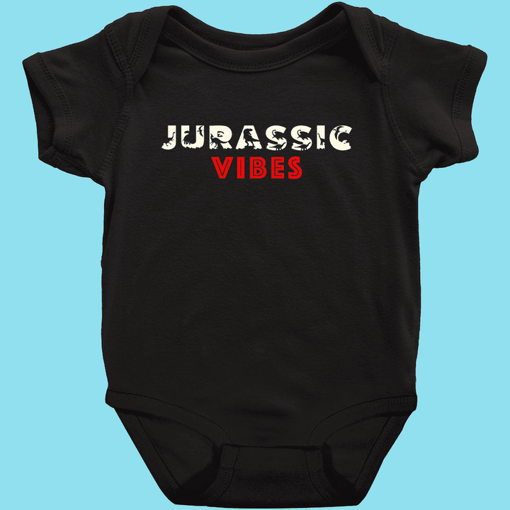 The Toddler Jurassic Vibes Onesie by Jurassic Studio features “JURASSIC” in cracked white and “VIBES” in bold red on a black, 100% cotton design. The playful style pops against a light blue background—perfect for your little one.