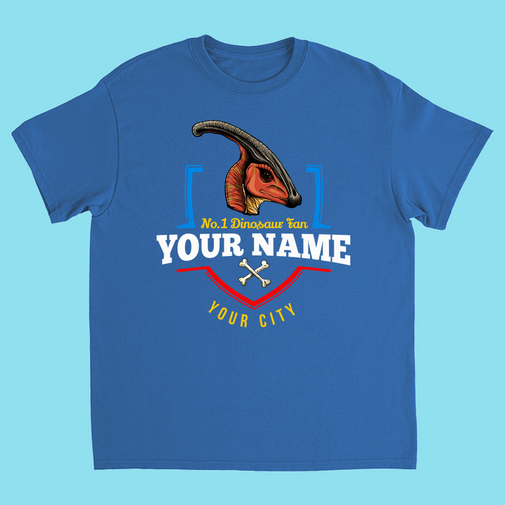 The N.1 Hadrosaur Fan Custom Kids T-shirt by Jurassic Studio features a blue shirt with an illustrated Parasaurolophus, crossed bones, and custom text—YOUR NAME YOUR CITY; a personalized dino gift with red, yellow, and blue accents.