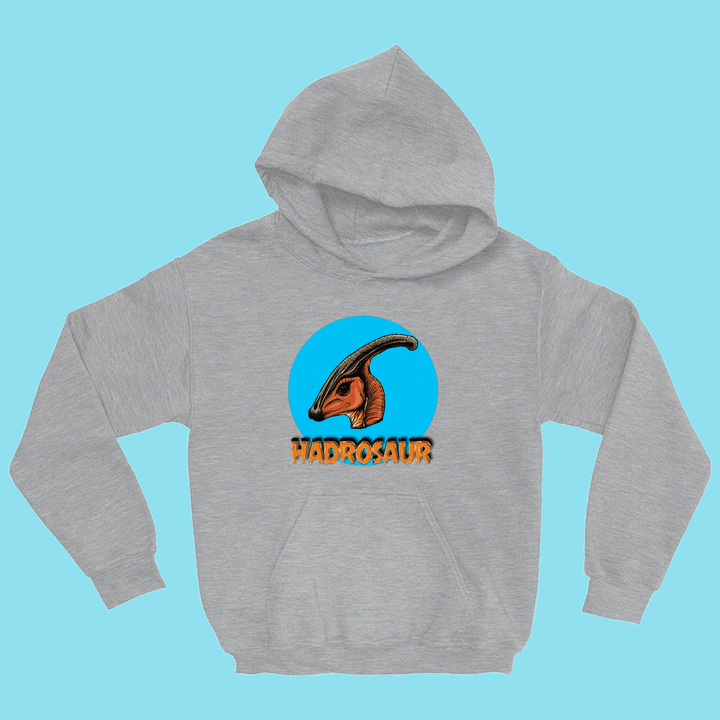 The Kids Hadrosaur Head Hoodie by Jurassic Studio features a gray hoodie with a colorful Parasaurolophus head in a blue circle and HADROSAUR in orange text below, standing out against a light blue background.