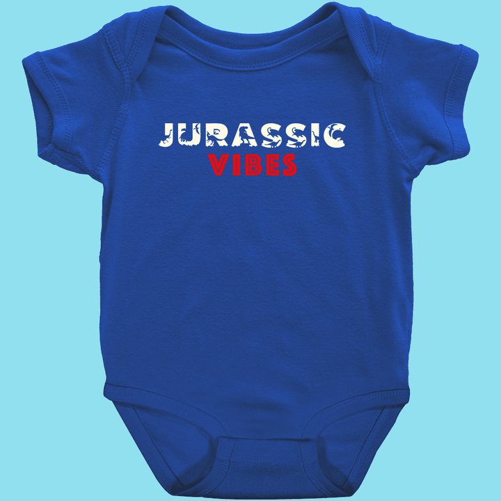 The Jurassic Studio Toddler Jurassic Vibes Onesie is a blue, 100% cotton bodysuit featuring JURASSIC in a dinosaur font and VIBES in bold red on the chest—perfect for your little dino fan!.