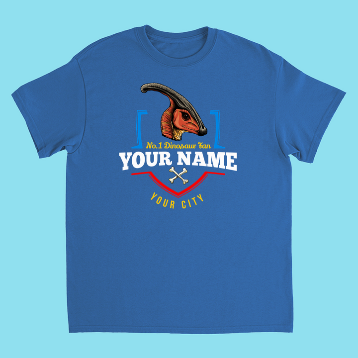Jurassic Studios N.1 Hadrosaur Fan Custom Kids T-shirt features a blue shirt with a colorful Parasaurolophus head, two crossed bones, and can be personalized with your name and city. Perfect dino gift for kids!.