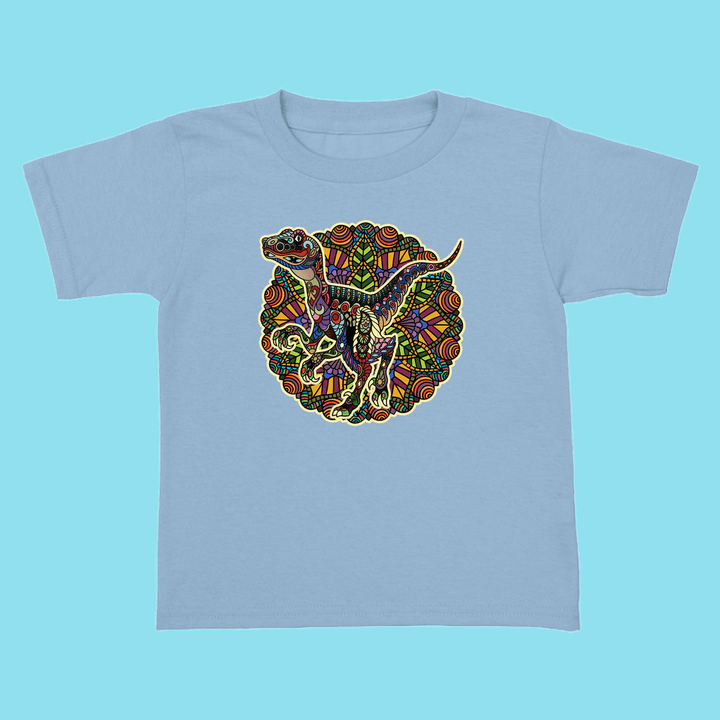 The Toddler Velociraptor Mandala T-Shirt by Jurassic Studio features a colorful mandala dinosaur design in the center, set against geometric patterns—a unique and perfect gift for young dinosaur fans.