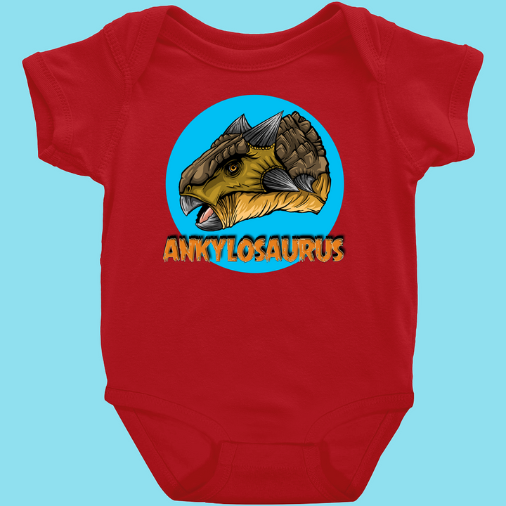 Jurassic Studio’s Toddler Ankylosaurus Head Onesie features a red cartoon ankylosaurus in a blue circle with “ANKYLOSAURUS” below—perfect for little dinosaur fans!.