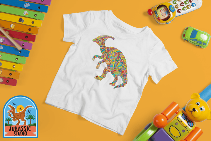 The Toddler Hadrosaur Zentangle T-Shirt by Jurassic Studio, featuring a colorful dinosaur graphic on 100% cotton, is shown on an orange background with toys—perfect for toddlers or as a gift for dinosaur fans.