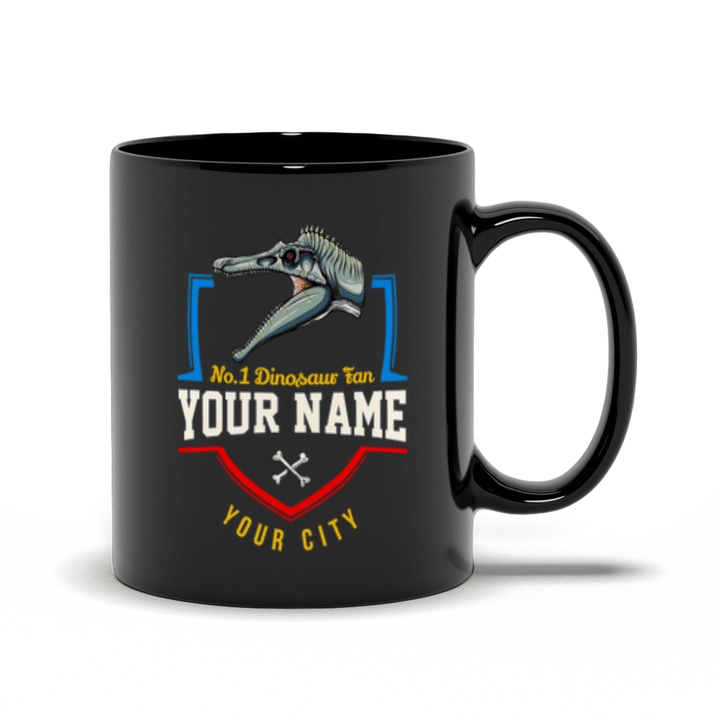 The Jurassic Studio N.1 Spinosaurus Fan Custom Mug features a black ceramic design with a dinosaur skull, bold No. 1 Dinosaur Fan YOUR NAME YOUR CITY,” blue and red accents, and crossed bones—perfect for any personalized Spinosaurus fan gift.