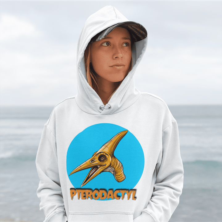 A woman in a Jurassic Studio Women Pterodactyl Head Hoodie stands by the cloudy seaside, gazing aside—an ideal scene for any dinosaur fan gift.