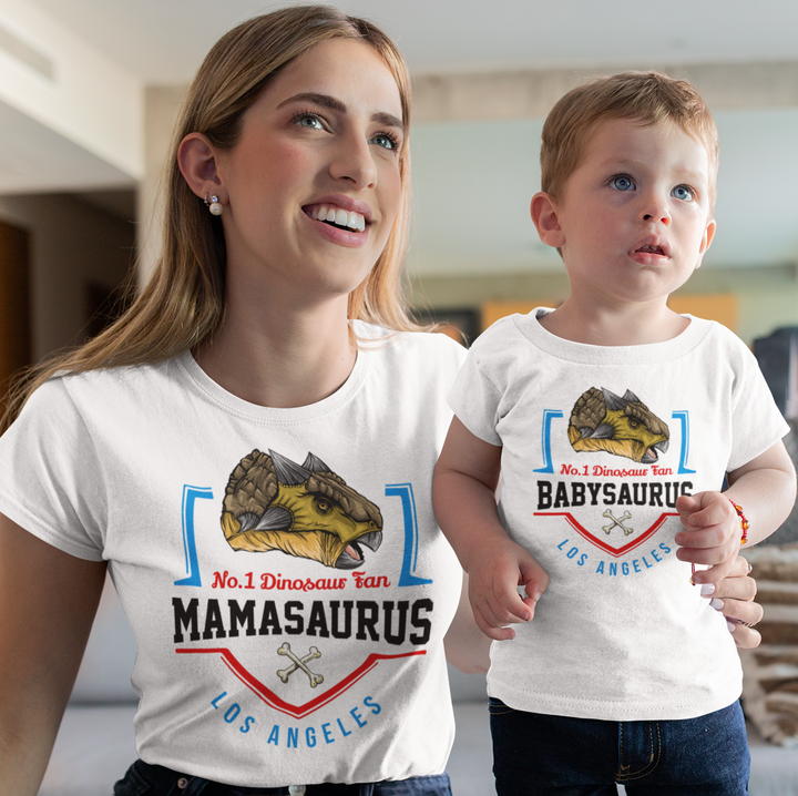 A woman and boy wear matching Jurassic Studio shirts with dinosaur graphics and Los Angeles; hers is a N.1 Ankylosaurus Fan Custom Women T-Shirt reading No. 1 Dinosaur Fan MAMASAURUS, his says No. 1 Dinosaur Fan BABYSAURUS.