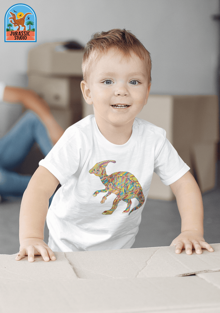 A smiling child wears the Jurassic Studio Toddler Hadrosaur Zentangle T-Shirt, showcasing a vibrant dino design on soft 100% cotton while leaning on a box indoors—an ideal gift for any dinosaur fan!.